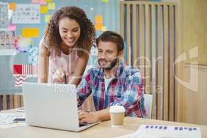 Graphic designers discussing over laptop