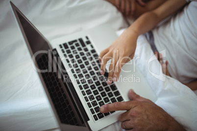 Parents and kids using laptop in bed