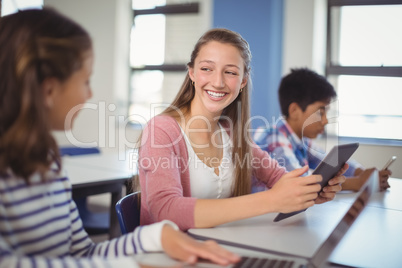 Students using digital tablet and laptop in classroom