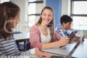 Students using digital tablet and laptop in classroom