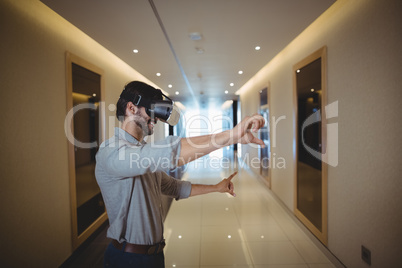 Male business executive using virtual reality headset in corridor