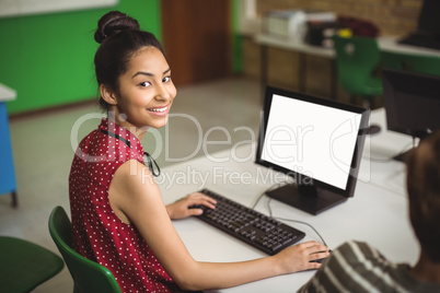 Portrait of smiling schoolgirl studying in computer classroom