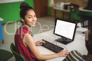 Portrait of smiling schoolgirl studying in computer classroom