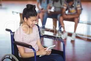 Disabled schoolgirl using digital tablet with classmates in background