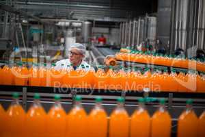 Factory engineer monitoring filled juice bottle on production line