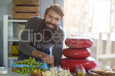 Portrait of salesman arranging cheese at counter