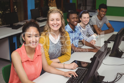 Portrait of smiling students studying in computer classroom