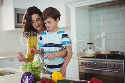 Mother and son mixing the salad in kitchen