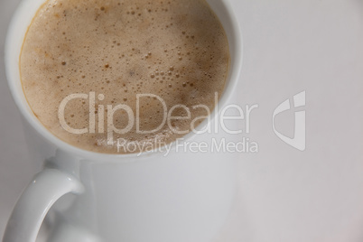 Close-up of white mug of coffee with creamy froth