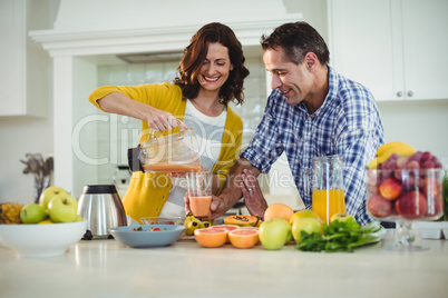 Happy couple preparing smoothie in kitchen