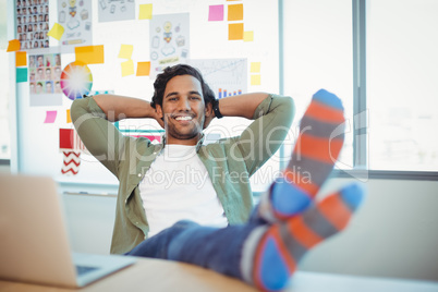 Male graphic designer relaxing with feet up at desk