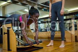 Trainer assisting woman with wunda chair in fitness studio