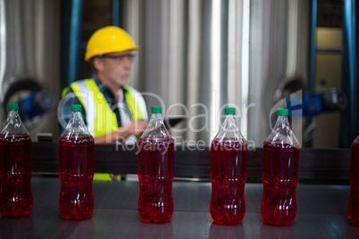 Male factory worker monitoring cold drink bottles