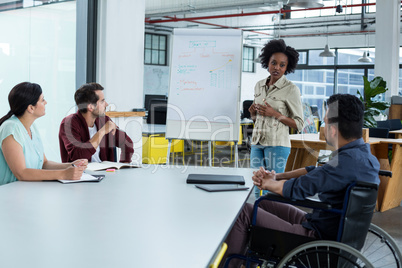 Business executives discussing over flip chart during meeting