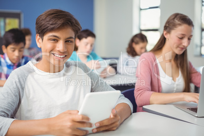 Students using digital tablet and laptop in classroom