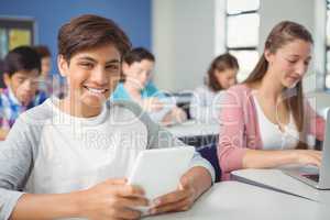 Students using digital tablet and laptop in classroom