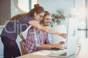 Graphic designers discussing over personal computer