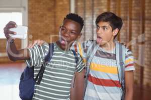 Happy schoolboys taking selfie on mobile phone in campus