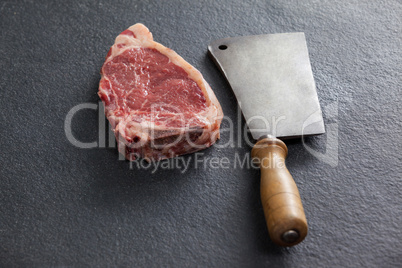 Sirloin chop and cleaver against black background