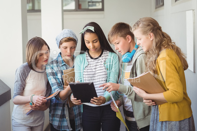 Group of school friends using digital tablet in corridor