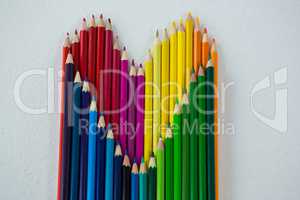 Colored pencils arranged in heart shape on white background