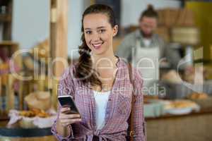 Portrait smiling woman using mobile phone at counter