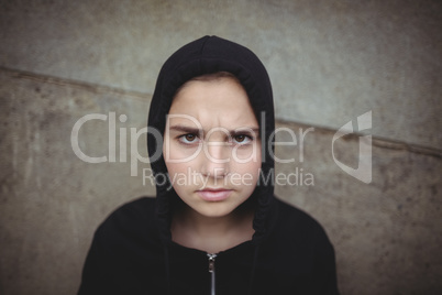 Anxious teenage girl in black hooded jacket standing at school