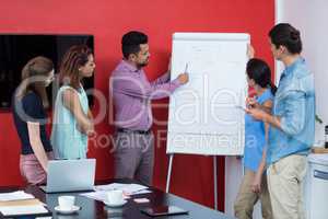 Business executives discussing over flip chart during meeting