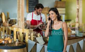 Smiling woman talking on mobile phone at counter