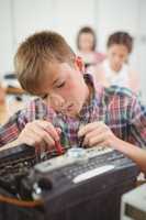 Schoolboy repairing a printer in the classroom