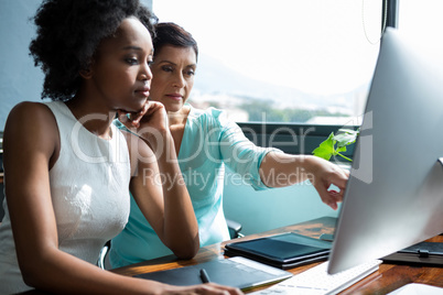 Female graphic designer pointing to desktop pc