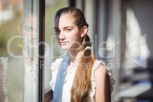 Portrait of schoolgirl standing near window in classroom