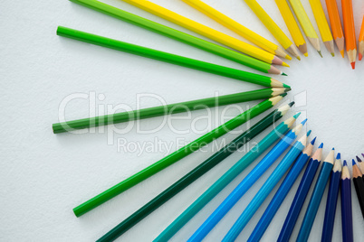 Colored pencils arranged in semi circle on white background