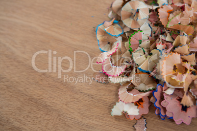 Colored pencils shavings on wooden background