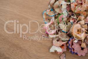 Colored pencils shavings on wooden background