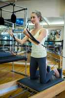 Determined woman practicing stretching exercise on reformer