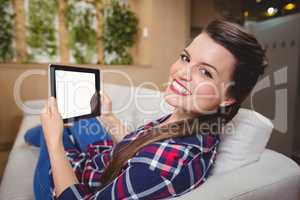 Portrait of female executive relaxing on sofa and using digital tablet