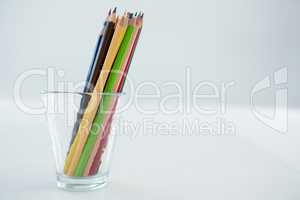 Colored pencils kept in glass on white background