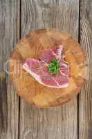 Sirloin chop and corainder leaves on wooden tray against wooden background