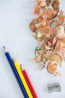 Colored shavings with colored pencils and sharpener on white background