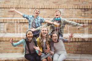 Portrait of smiling school students sitting on staircase having fun in campus