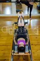 Determined woman practicing stretching exercise on reformer