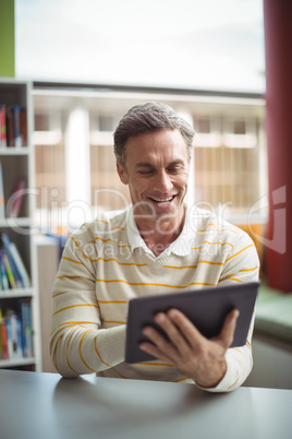 Attentive school teacher using digital tablet in library Attentive school teacher using digital tablet in library