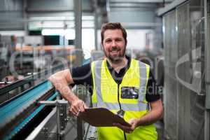 Portrait of factory worker standing with clipboard