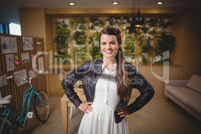 Portrait of smiling female executive standing with hands on hip