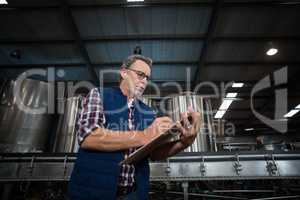 Factory worker writing on clipboard in factory