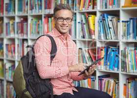 Portrait of happy school teacher using digital tablet in library