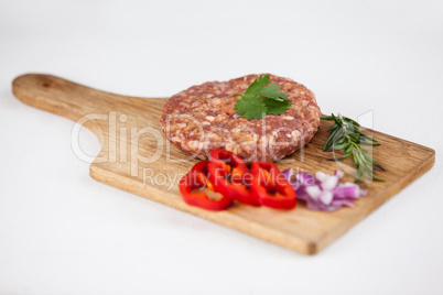 Beef patty and ingredients on wooden tray