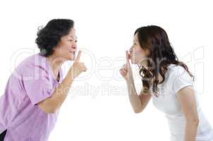 Mother and daughter finger on lips