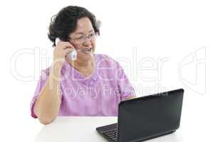 Senior adult woman using phone and computer
